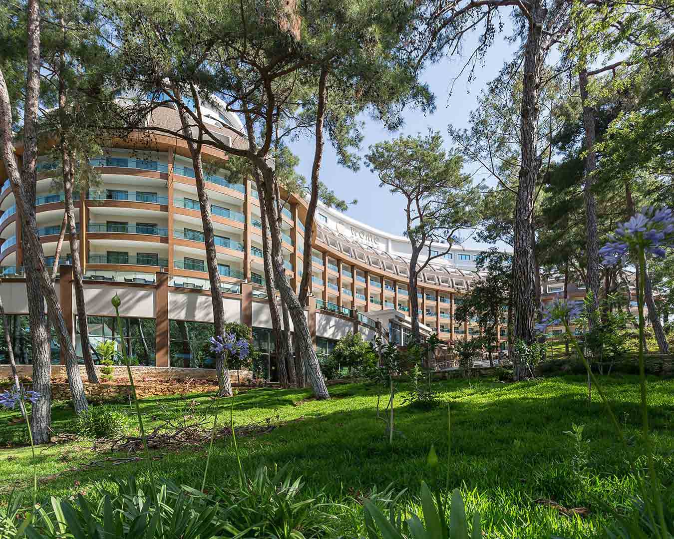 Çam ağaçlarının arasındaki otel binası ve bahçesi